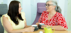 Two women smiling and chatting over a cup of tea