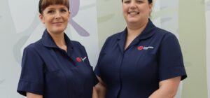 Two white nurses in dark blue uniform standing together