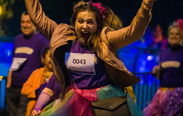Young woman dressed in bright clothing cheering along the Treetops Moonlight Walk