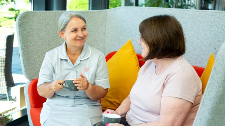 Treetops Healthcare assistant chatting to a patient over a cup of tea