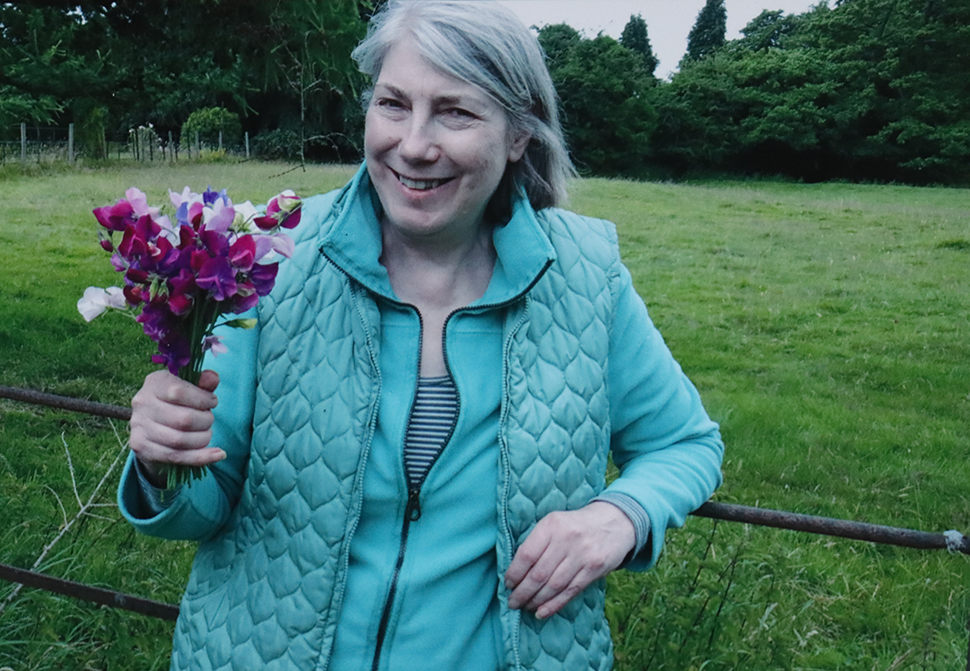 Smiling woman with turquoise jacket holding flowers