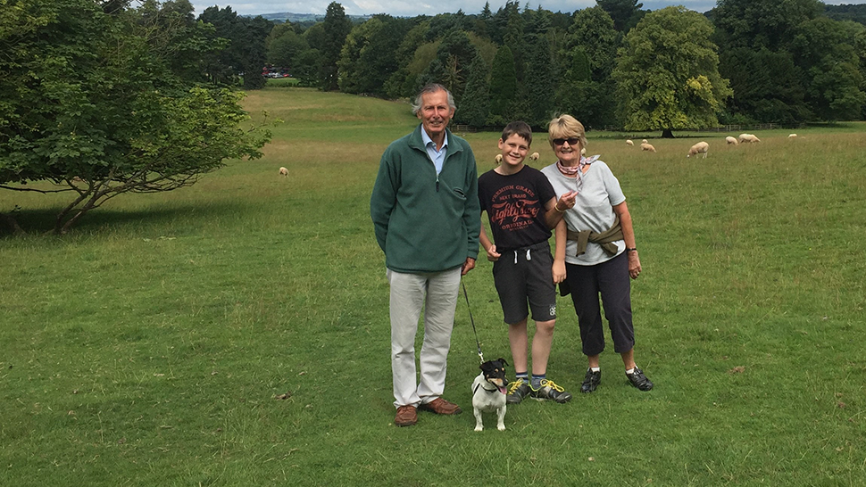 Two grandparents standing beside their grandson and dog during a walk