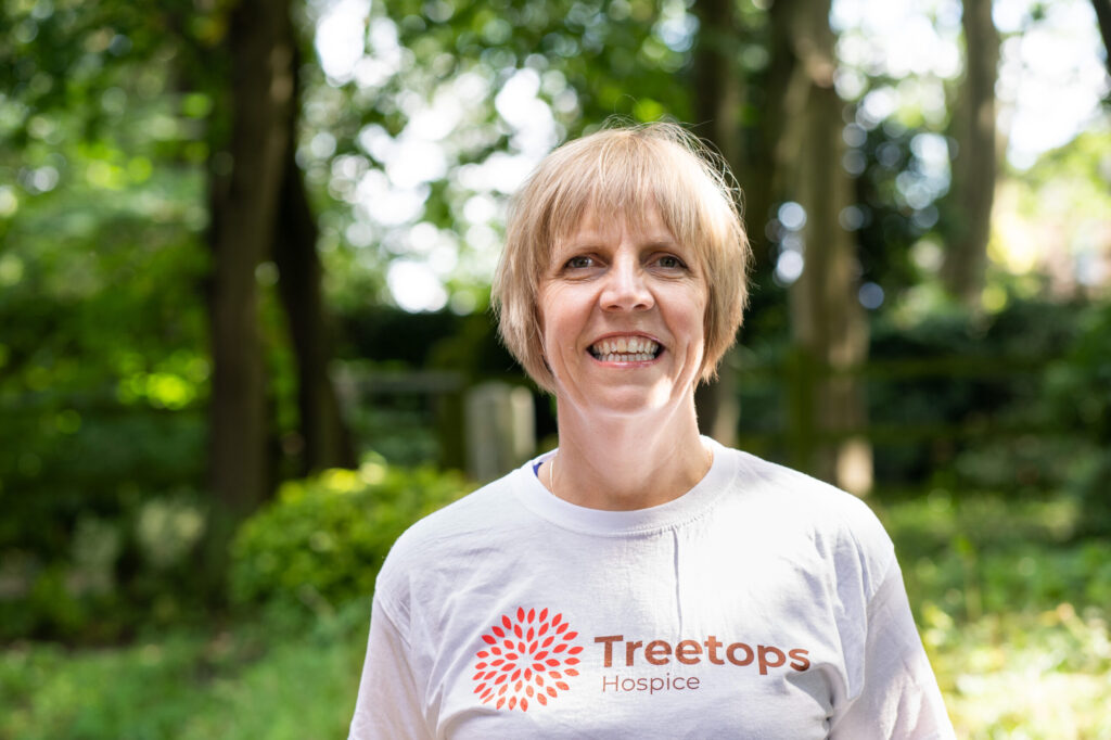 Woman with short blonde hair in Treetops t-shirt standing outside in sunshine