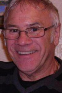 Man with grey hair and glassed smiling at camera