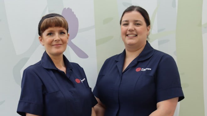 Two women in dark blue Treetops nurse uniforms smiling