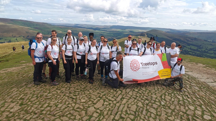 Large group of walkers on top of a hill wearing Treetops t-shirts and holding a Treetops banner