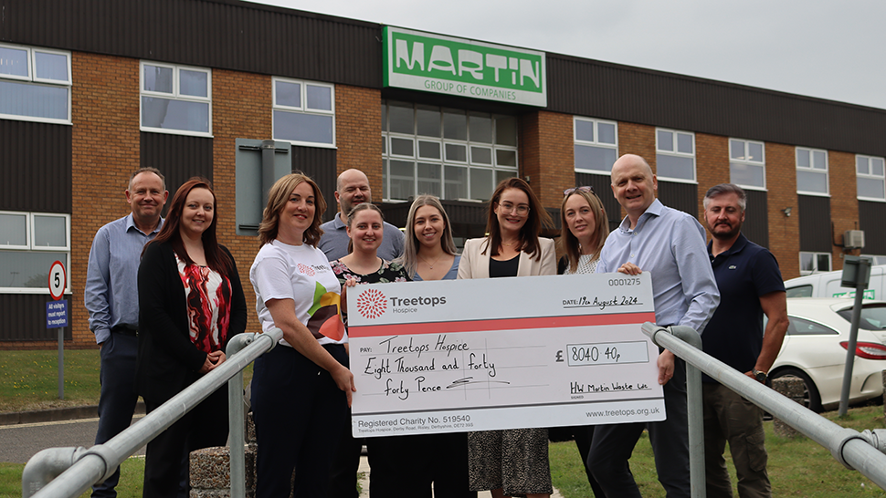 Group of people standing with a large cheque outside HW Martin Waste Ltd