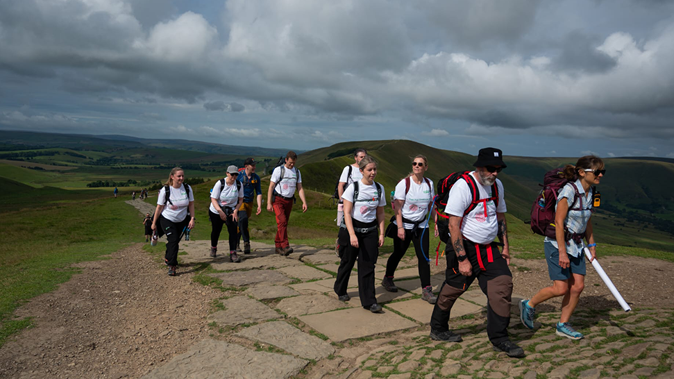 Groups of people walking up a hill with rucksacks and wearing Treetops t-shirts