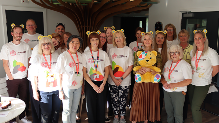 Group of adults in Treetops t-shirts celebrating in the Treetops counselling centre for bereaved children