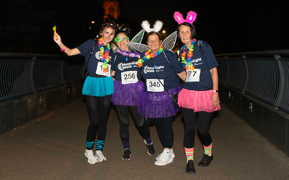 four women smiling in Moonlight Walk t-shirts and fancy dress. Photo credit: JMS Photography